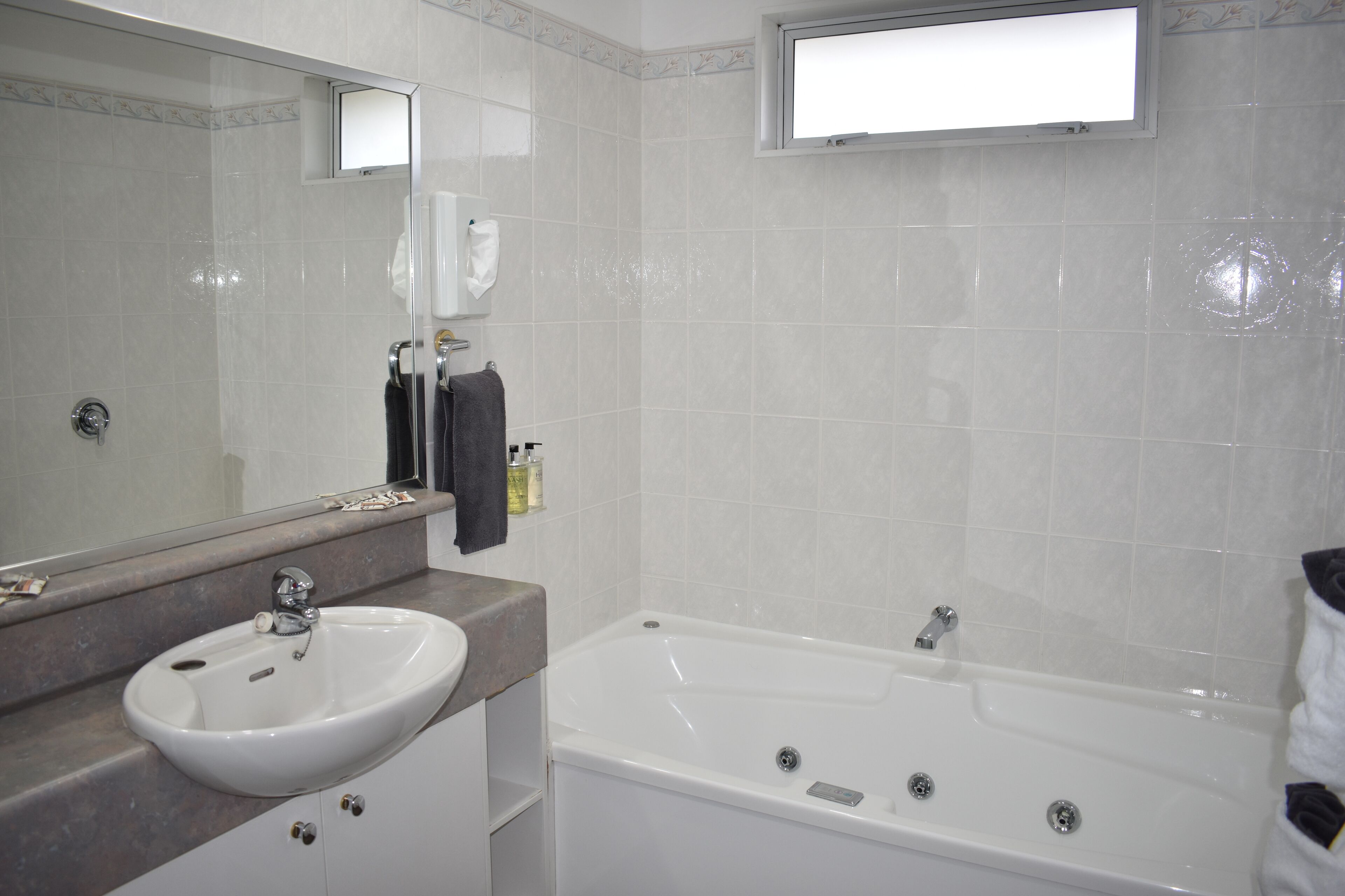 A bathroom with a white sink, a bathtub, and a mirror.
