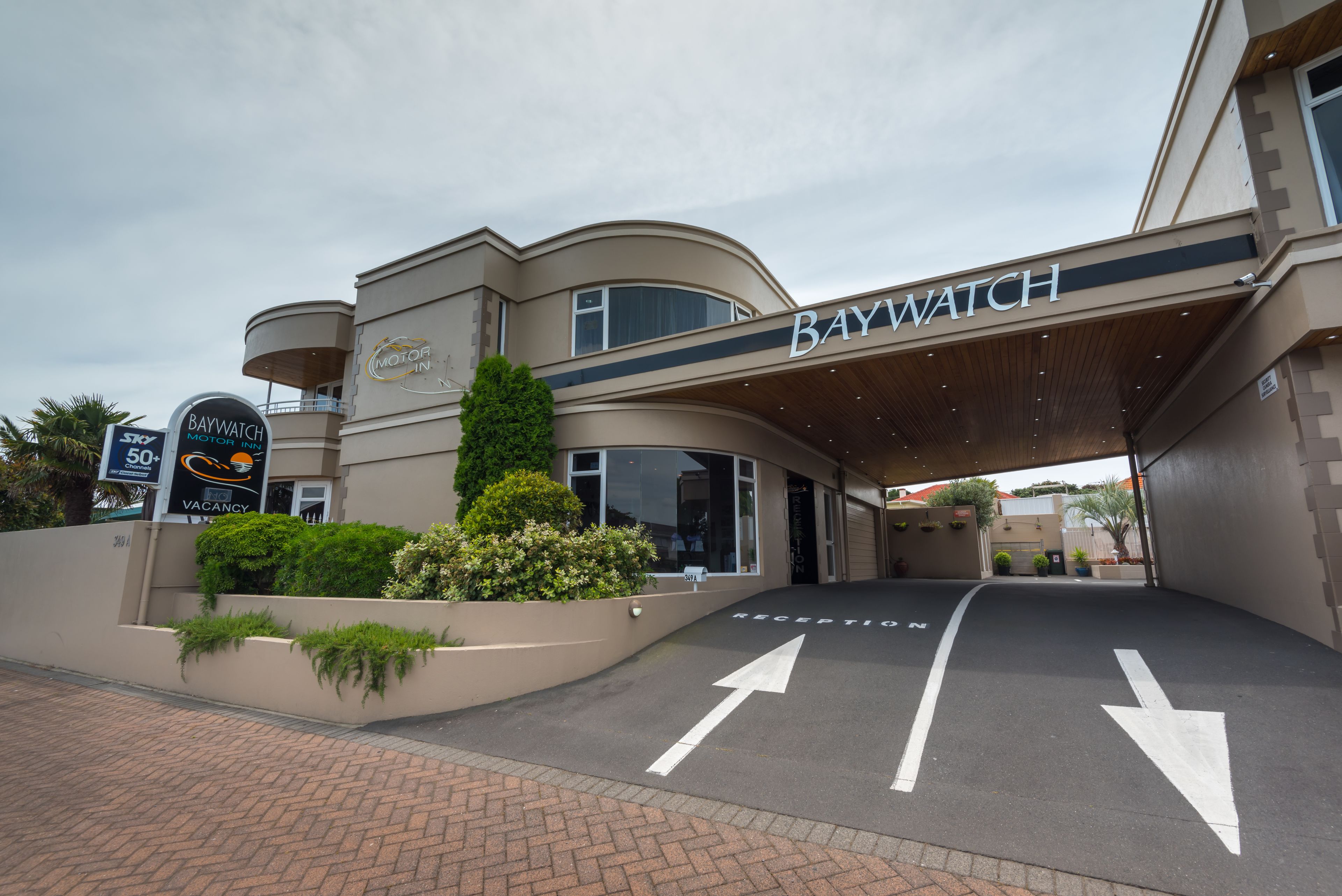 A hotel entrance with a sign reading "Baywatch Motor Inn."