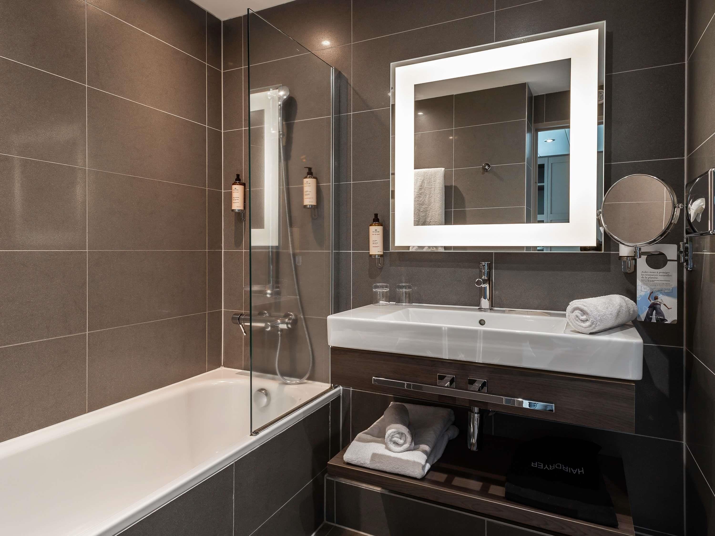 A modern bathroom with a glass-enclosed shower, a white sink, and a large mirror.