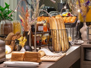 Un buffet proposant une variété de plats, notamment du pain, des pâtisseries et des condiments.