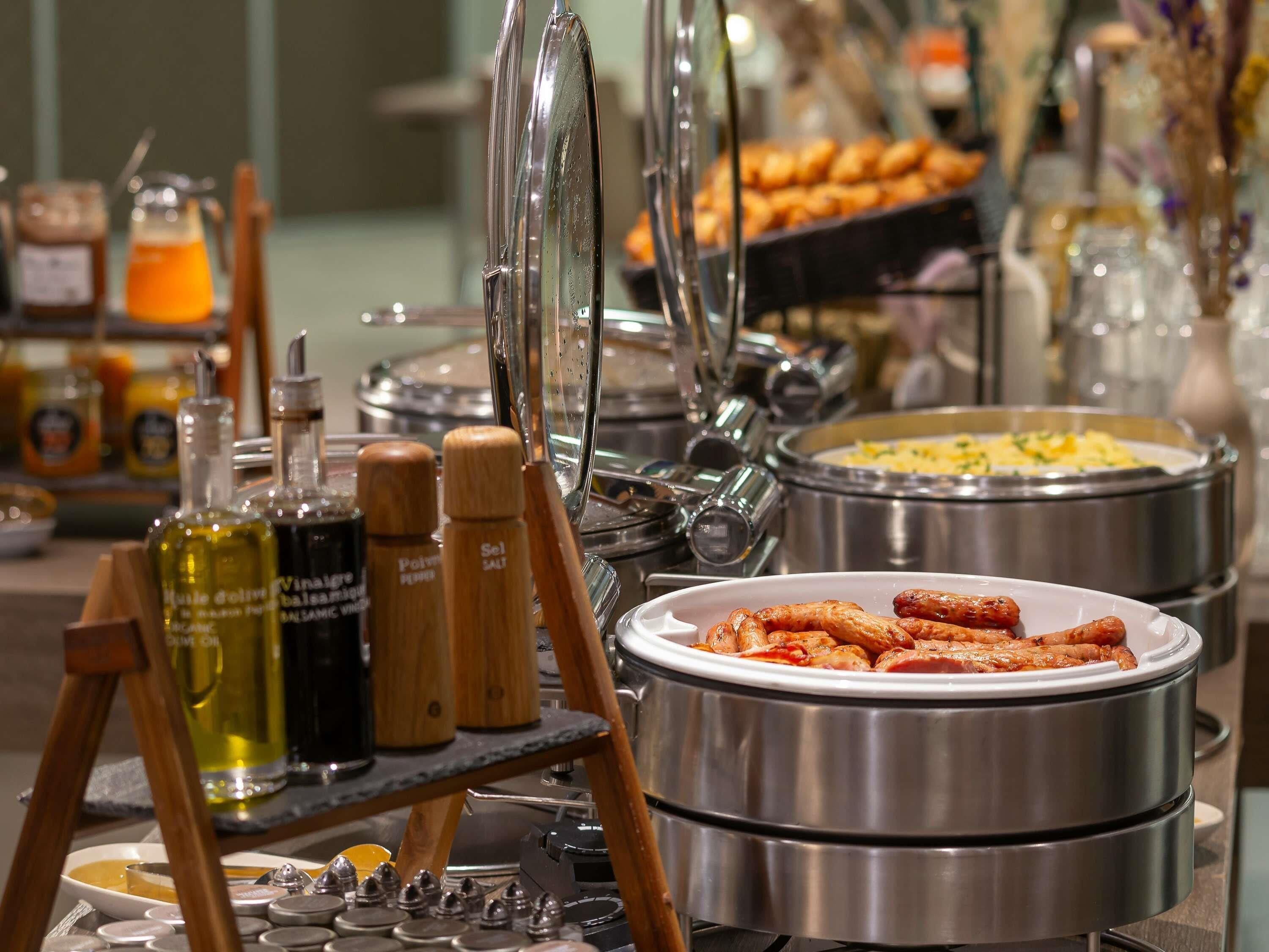 A buffet setup with various food items, condiments, and cooking equipment.