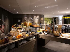 A buffet with various food items and beverages, a coffee station, and a dining area with tables and chairs. - Mercure Clermont Ferrand Centre Jaude (Clermont-Ferrand)