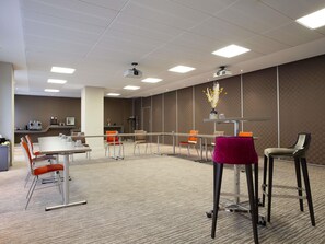 A conference room with a long table, chairs, a projector, and a carpeted floor.