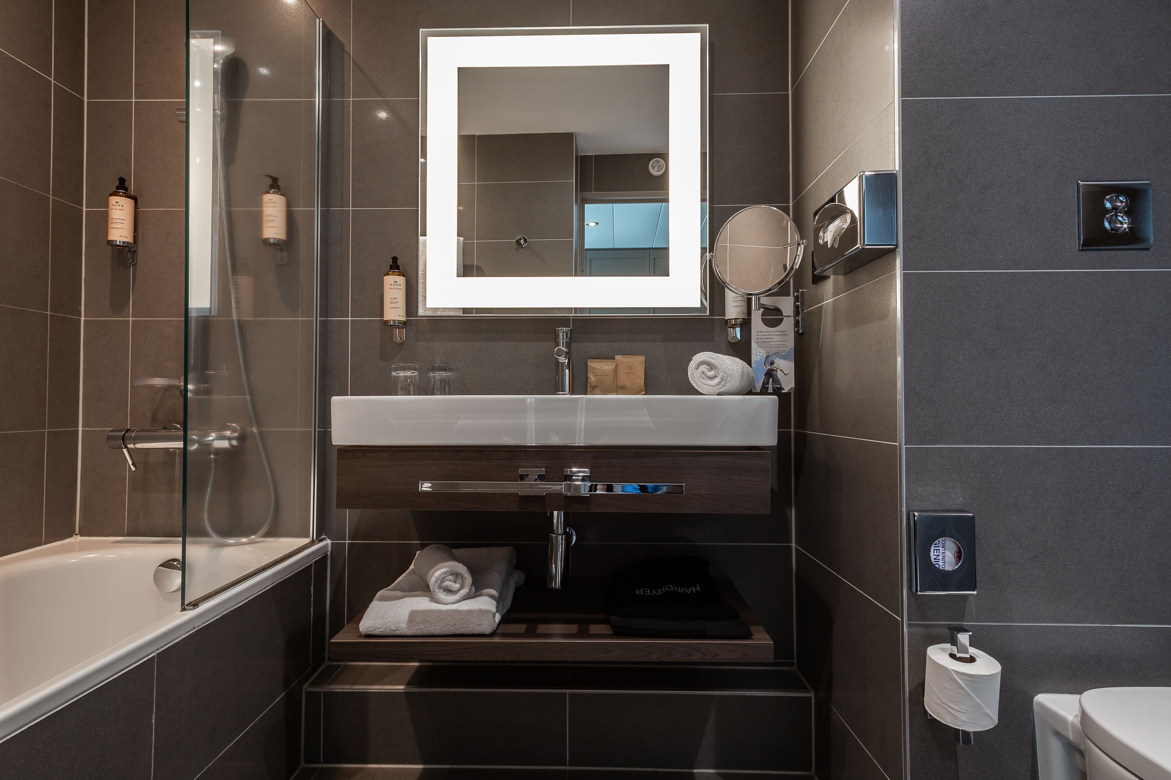 Ein modernes Badezimmer mit einer Duschkabine aus Glas, einem Waschtisch mit Spiegel und einer Toilette.