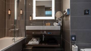 Ein modernes Badezimmer mit einer Duschkabine aus Glas, einem Waschtisch mit Spiegel und einer Toilette.