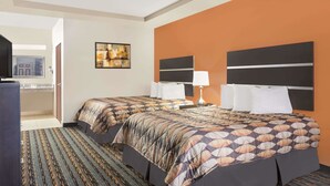 A hotel room with two beds, a TV, a painting on the wall, and a bathroom visible through an open door. - Days Inn by Wyndham Dilley (Dilley)