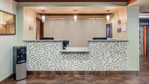A reception area with a water dispenser, a reception desk, and a wall-mounted sign. - Days Inn by Wyndham Dilley (Dilley)