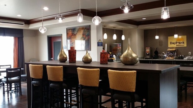A bar area with a long counter, multiple hanging pendant lights, and several chairs. - Days Inn by Wyndham Dilley (Dilley)