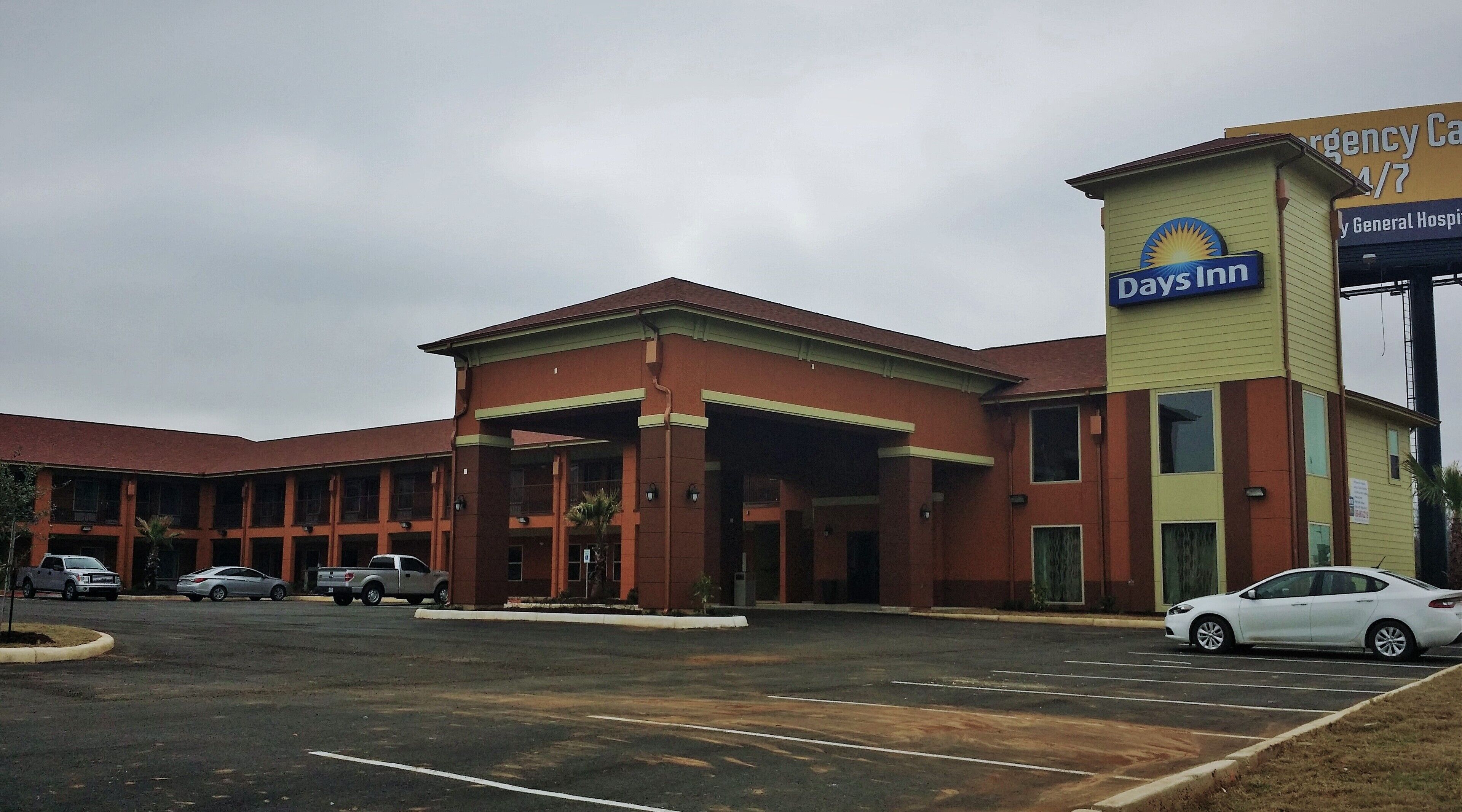 A Days Inn with a parking lot and a building with a red facade and a yellow sign.