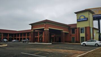 A Days Inn with a parking lot and a building with a red facade and a yellow sign.