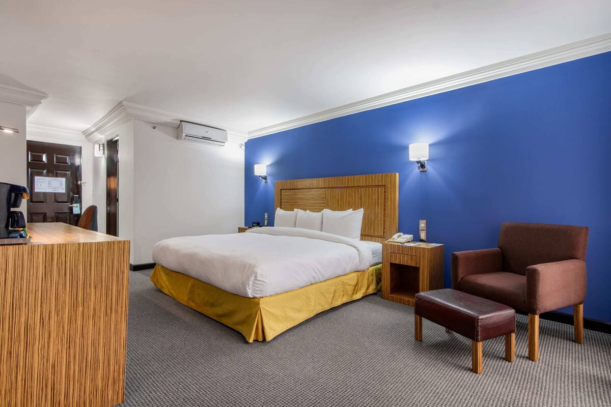 A hotel room with a bed, a desk, a chair, and a nightstand.