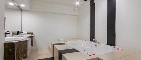A modern bathroom with a large bathtub, two sinks, and a mirror.
