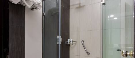 Ein modernes Badezimmer mit Toilette, einer gläsernen Dusche und einem Handtuchhalter mit Handtüchern.