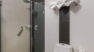 A modern bathroom with a toilet, a glass shower enclosure, and a towel rack.