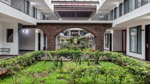 A spacious atrium with a central garden, a staircase, and a modern design with white walls and metal railings. - Radisson Hotel & Convention Center Toluca (Toluca)