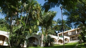 Un hotel con múltiples arcos y un exuberante jardín de palmeras.