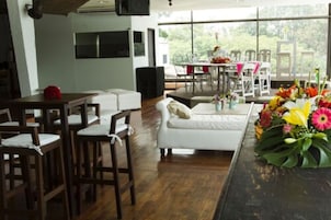 Una sala de estar moderna con un sofá blanco, sillas de madera, una mesa de comedor y un ventanal que ofrece vistas al exterior.