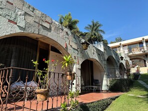 A courtyard with stone walls, arched doorways, and potted plants. - Hotel Villa del Conquistador (Cuernavaca)