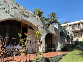 Un patio con muros de piedra, arcos y macetas con plantas.