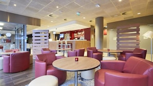 Een moderne loungeruimte met lederen zitplaatsen, een bar en een televisiescherm.