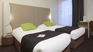 Een hotelkamer met twee bedden, een bureau en een stoel.