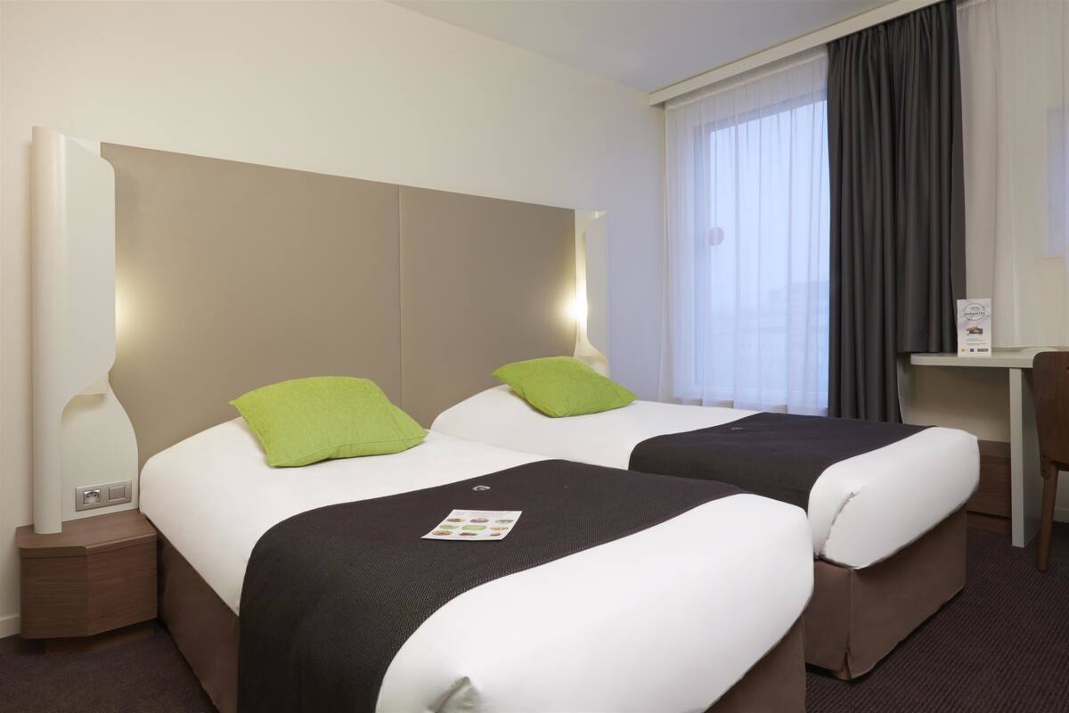 Une chambre d’hôtel avec deux lits, un bureau et une chaise.