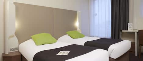 A hotel room with two beds, a desk, and a chair.