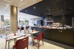 Um restaurante moderno com balcão central, mesas para refeições e cadeiras vermelhas.