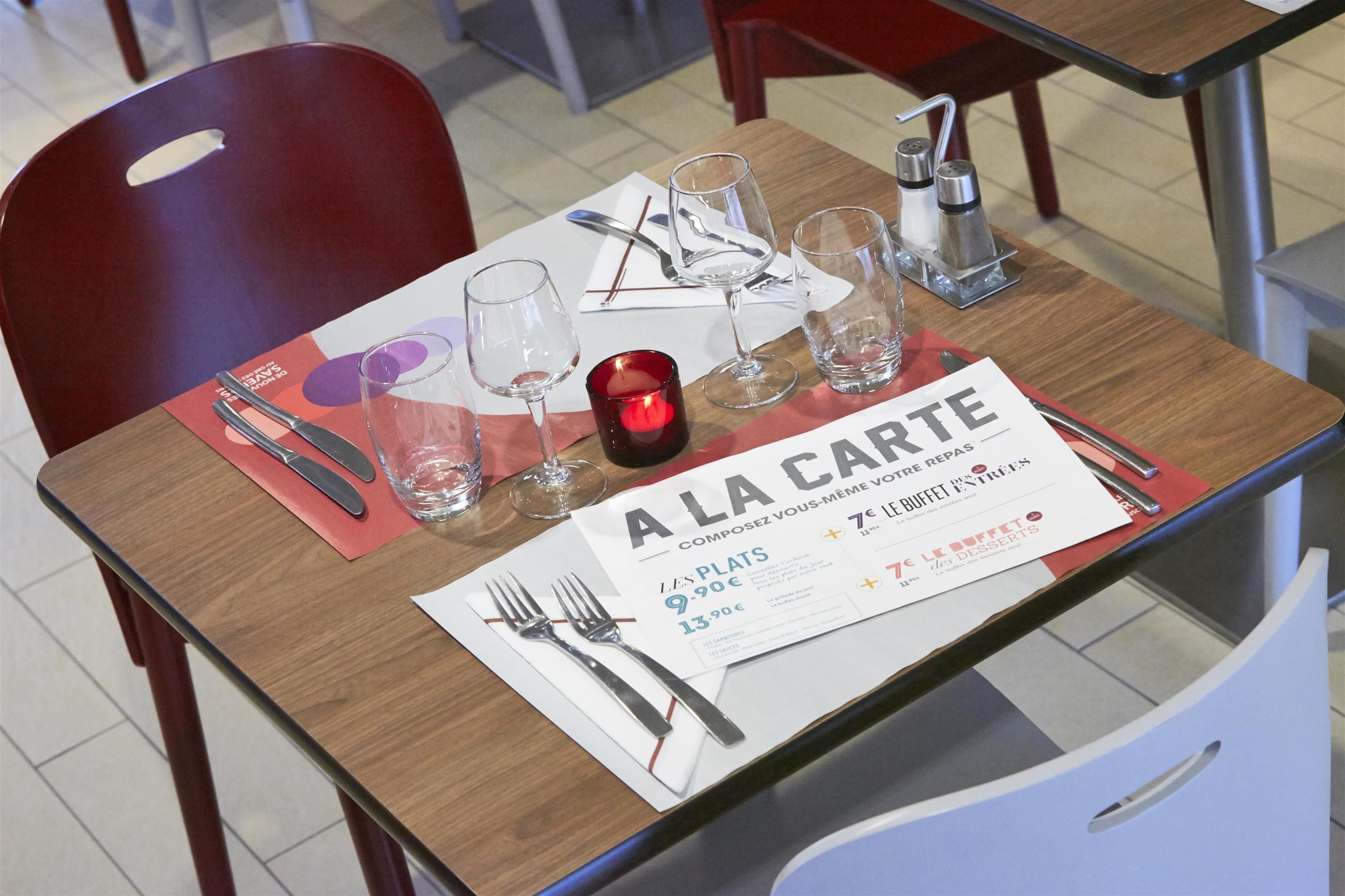 Une table à manger dressée avec un menu, des verres à vin et des couverts.