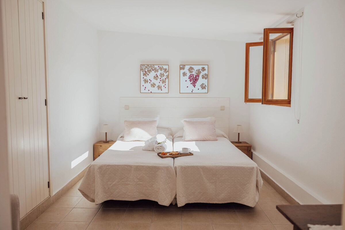 A double bed with a tray of breakfast items, two bedside tables, and two framed artworks on the wall.