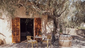 An outdoor seating area with wicker chairs, a round table, and a wooden barrel. - Hotel Rural Can Feliu (Porreres)