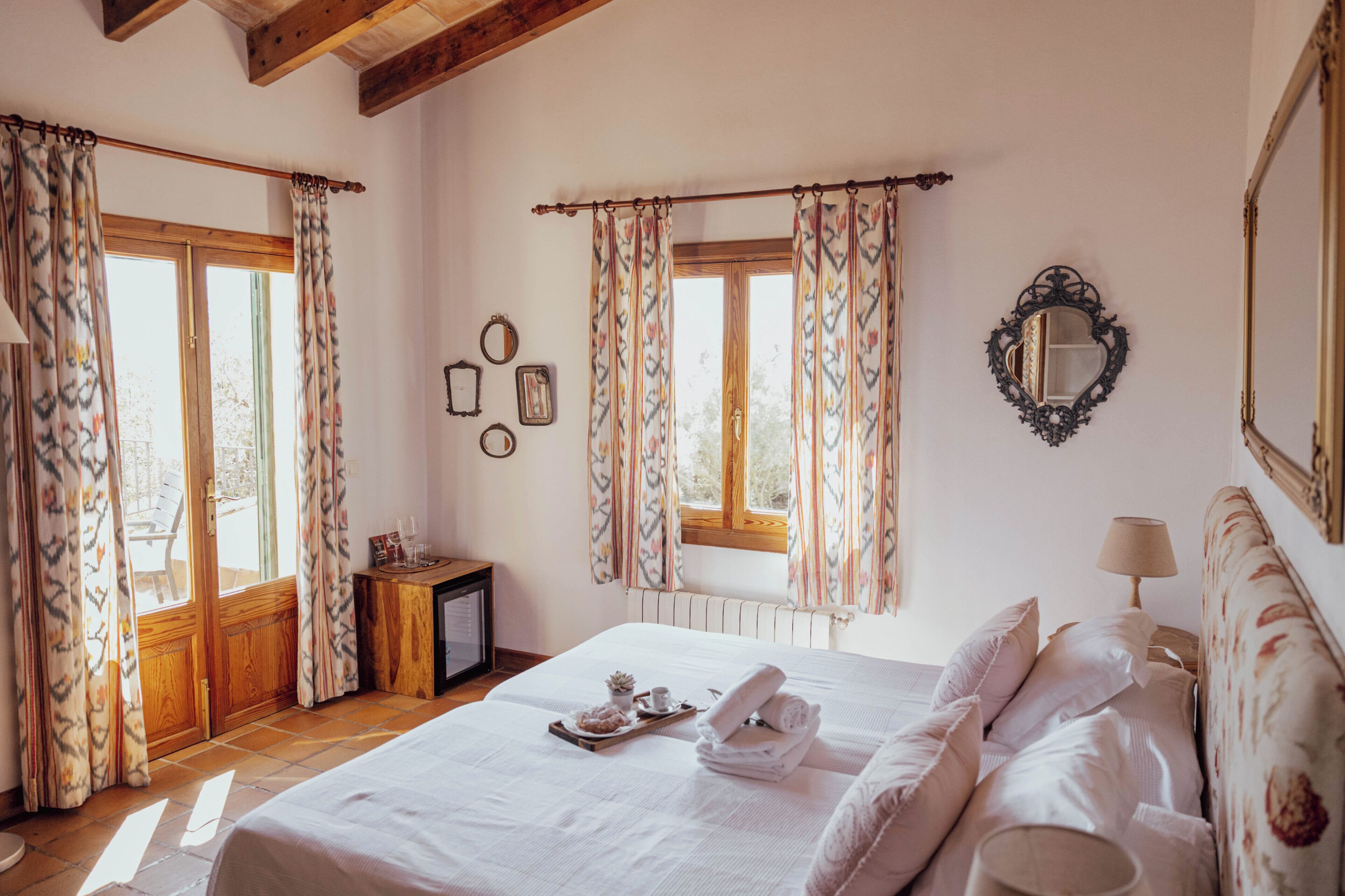 A bedroom with a bed, curtains, a dresser, a mirror, and a window.