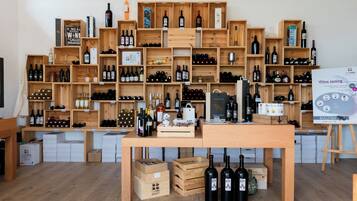 Una sala de degustación de vinos con estantes de madera que exhiben varias botellas y una mesa con más botellas y un cartel sobre la degustación.