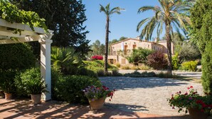 A stone pathway leading to a stone building with a white pergola and lush greenery. - Hotel Rural Can Feliu (Porreres)
