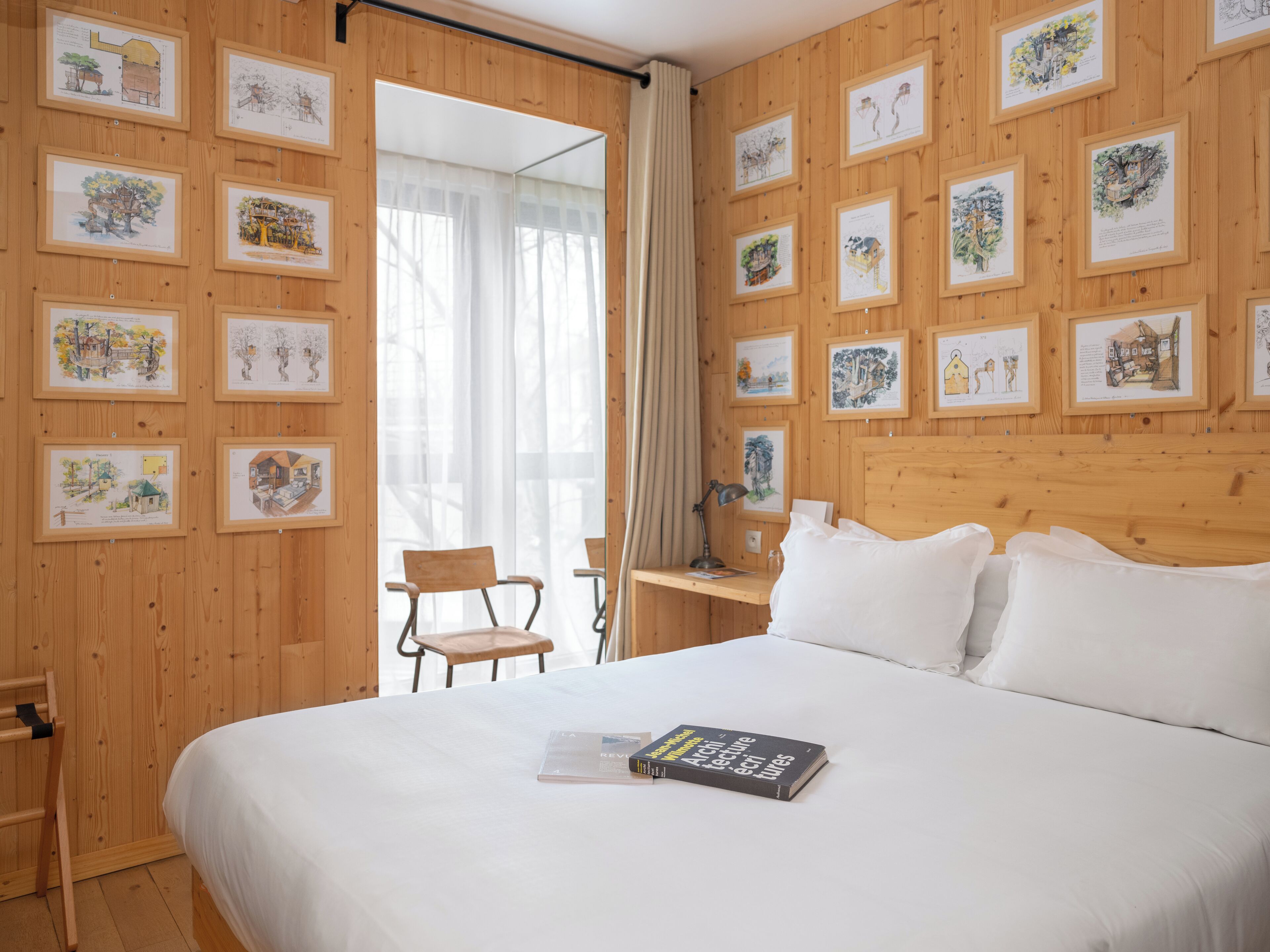 Una habitación de hotel con una cama grande, cabecero de madera e ilustraciones enmarcadas en las paredes.