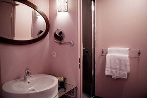 A bathroom with a sink, mirror, towel rack, and a shower.