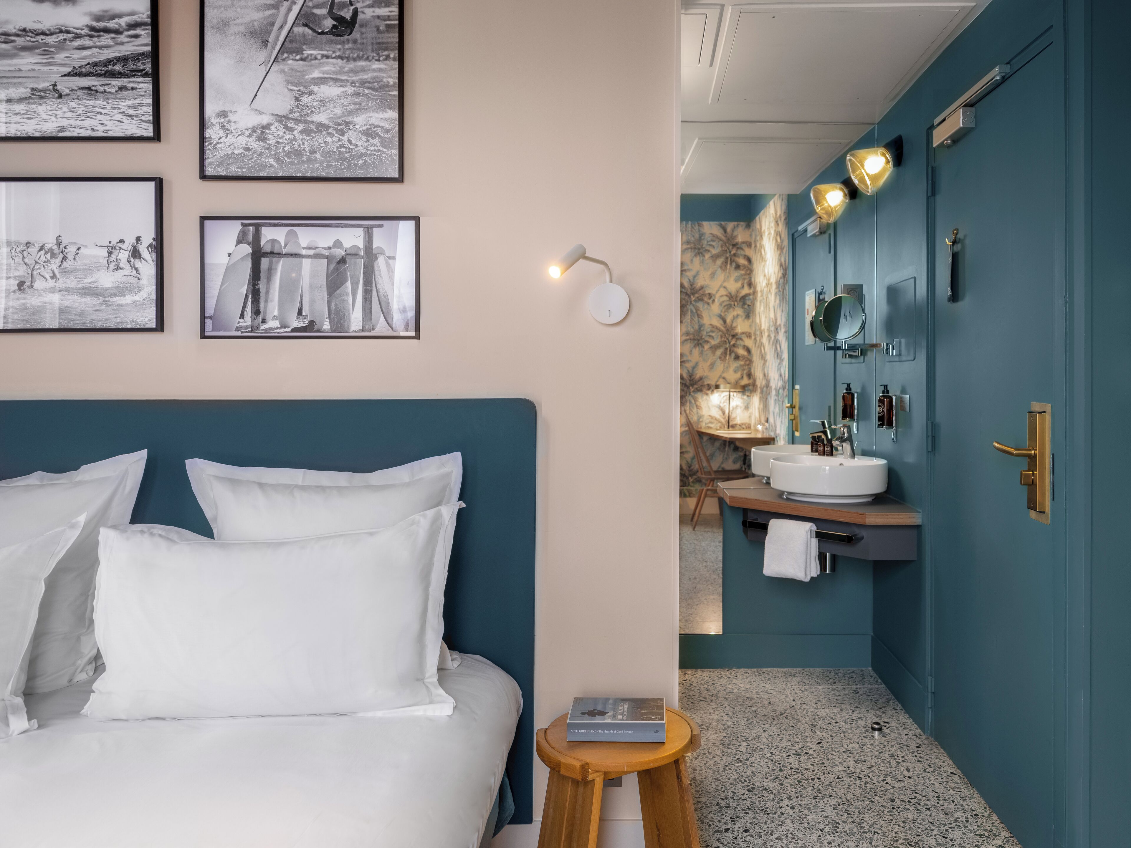 A bedroom with a bed, a bedside table, and a wall with framed pictures.
