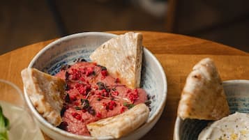 Una mesa con varios platos, incluyendo un tazón de carne, un tazón de hummus y una taza de té.