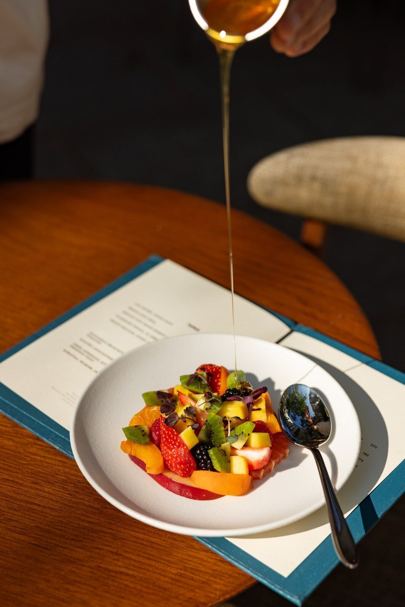 Un plato de ensalada de frutas con una cuchara sobre una mesa.