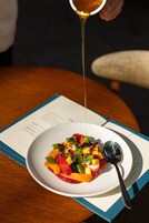 A plate of fruit salad with a spoon on a table.
