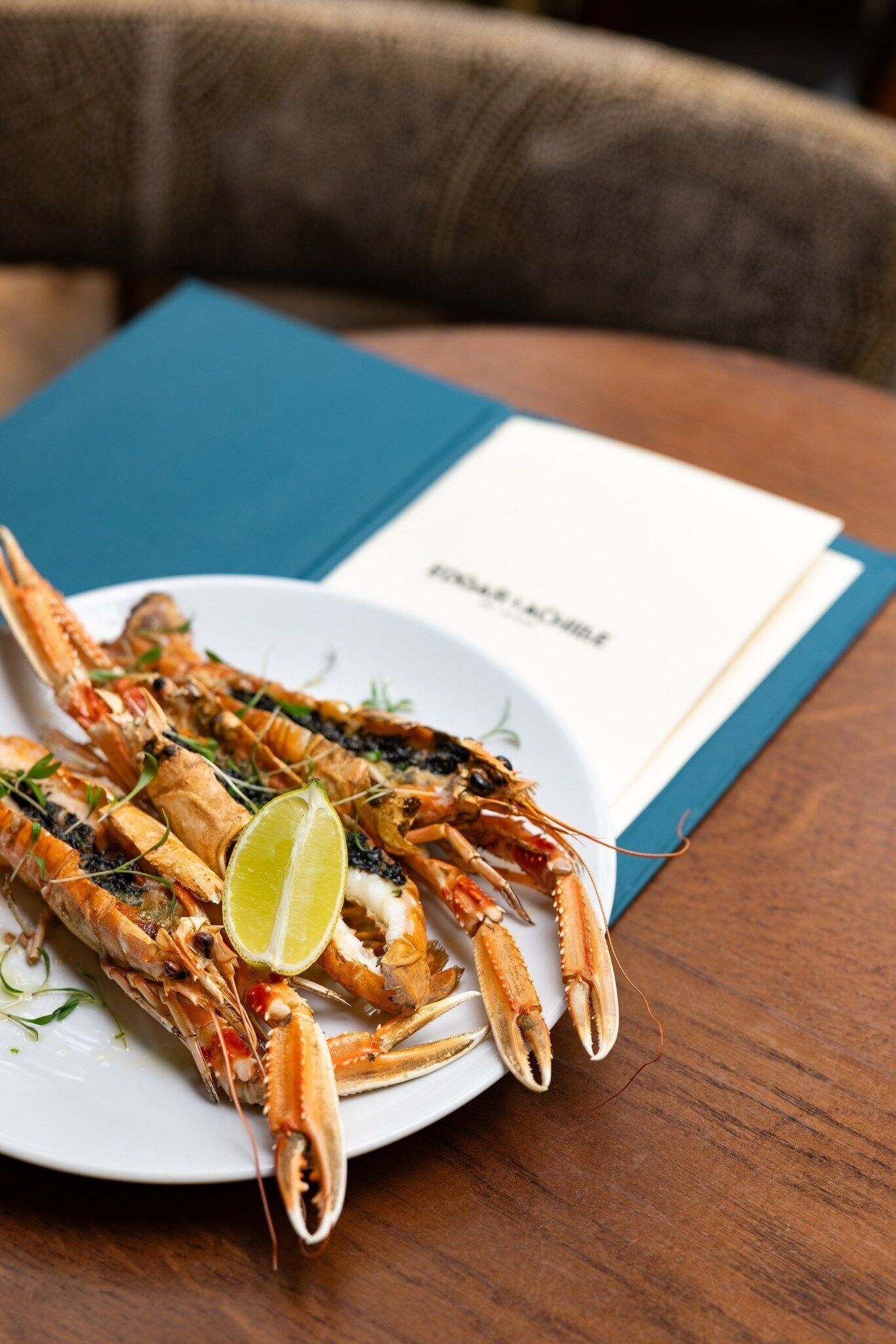 A plate of cooked lobster on a table with a menu in the background.