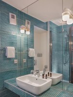 Un baño con un espejo grande, dos lavamanos y una ducha.