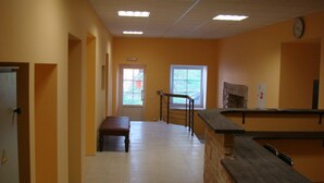A hotel room with a large window, a bench, a counter, and a clock on the wall. - Fortuna Hostel (Vilnius)
