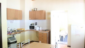 A kitchen with wooden cabinets, a microwave, and a refrigerator. - Fortuna Hostel (Vilnius)