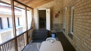A covered outdoor area with a table and chairs, a staircase leading to an interior space, and a brick wall. - Fortuna Hostel (Vilnius)