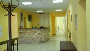 A hallway with a reception desk, a bench, and a staircase. - Fortuna Hostel (Vilnius)