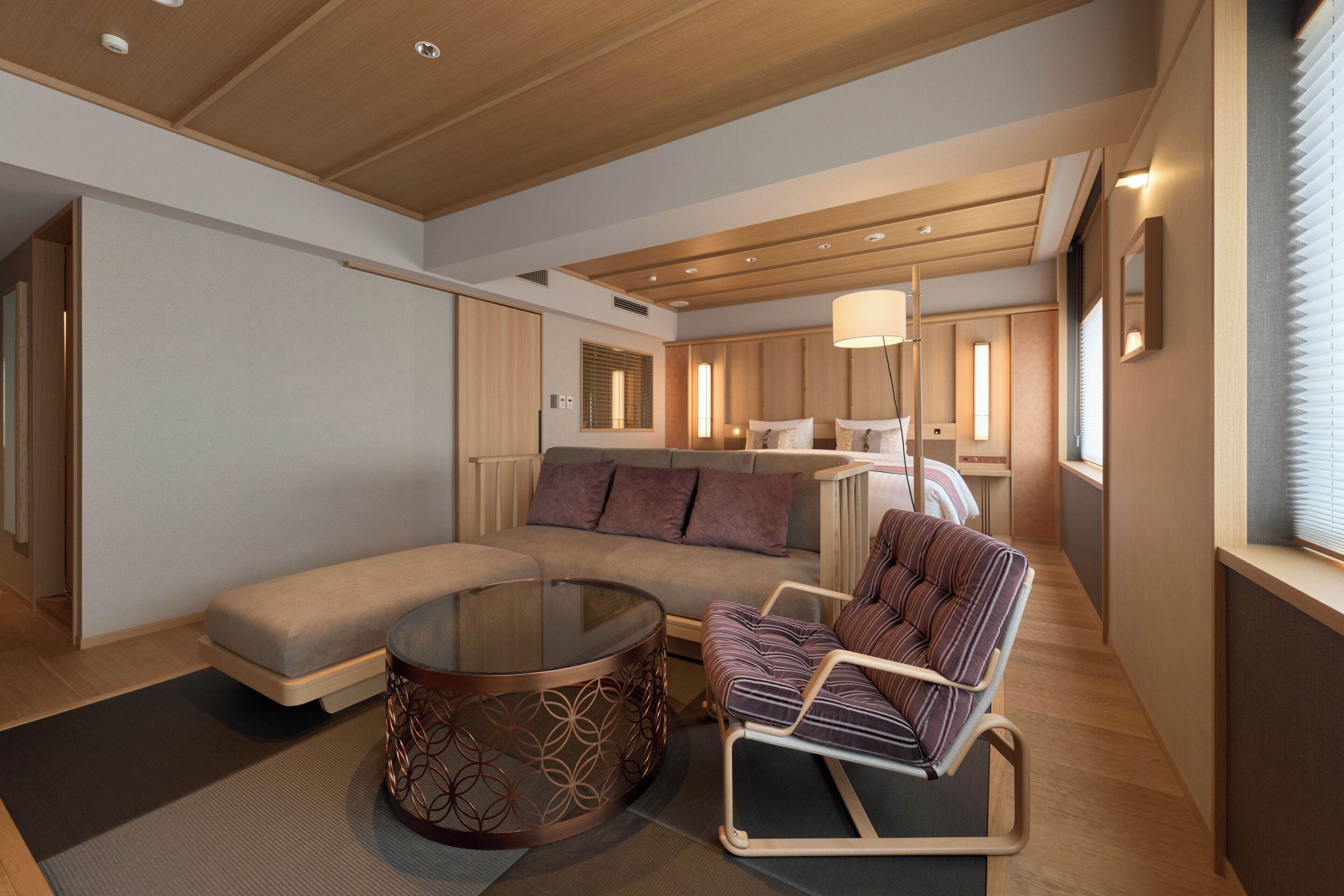 A modern interior with a sofa, a round coffee table, and a striped armchair.