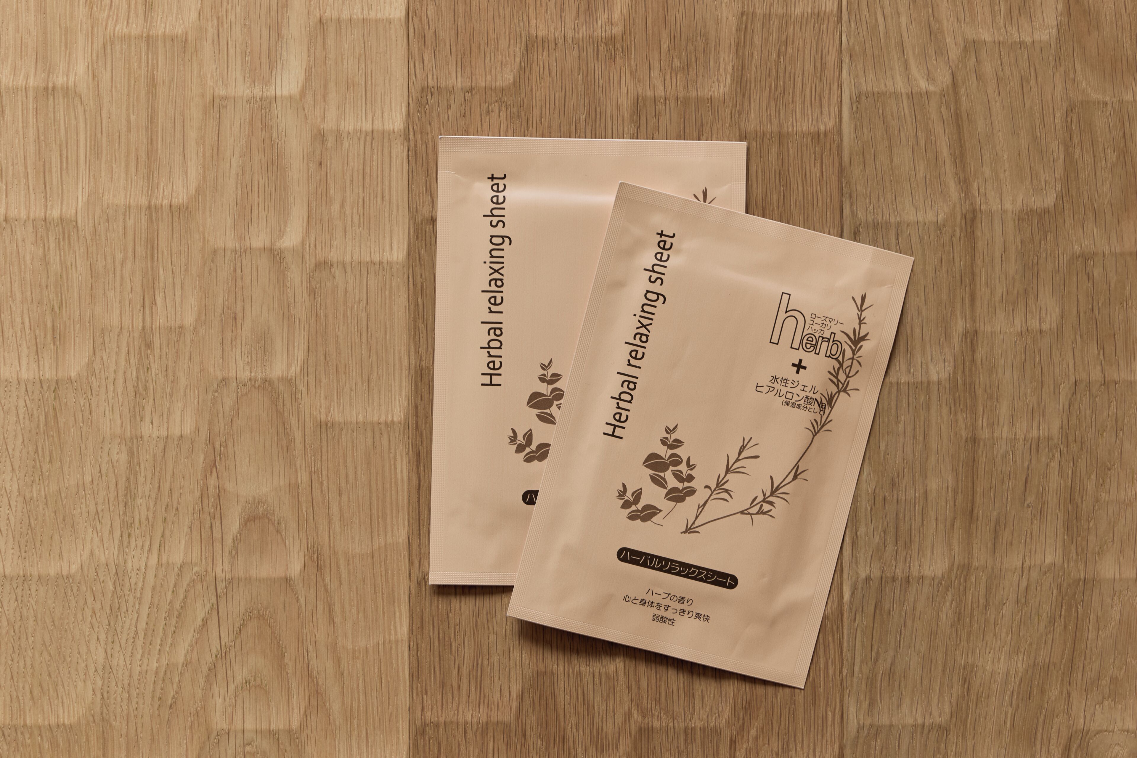 Two brown paper bags labeled 'Herbal relaxing sheet' on a wooden surface.