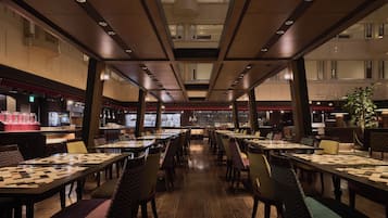 A spacious restaurant with high ceilings, multiple dining tables, and a variety of seating options.
