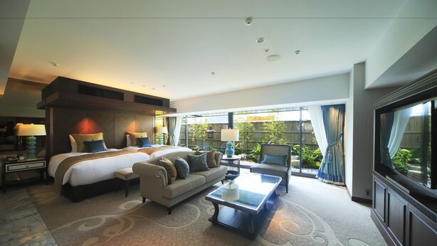 Una habitación de hotel moderna con una cama grande, un sofá, una mesa de centro y un televisor.